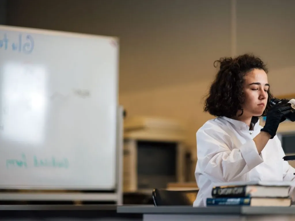 Technicienne de laboratoire au microscope, en blouse blanche