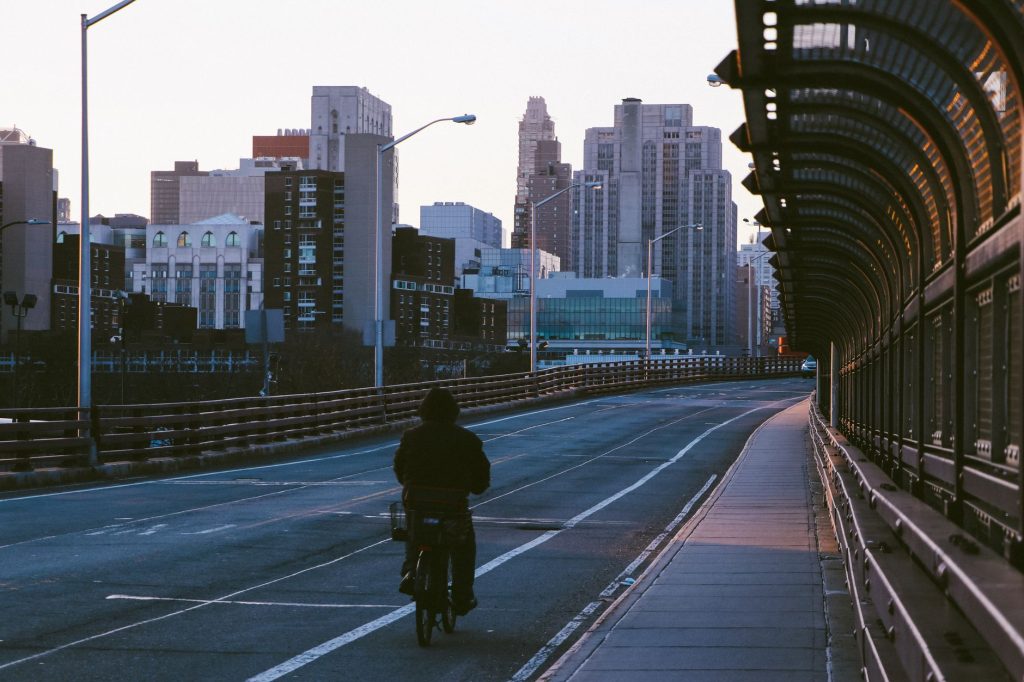Un cycliste seul traverse un pont urbain tôt le matin, gratte-ciel en arrière-plan