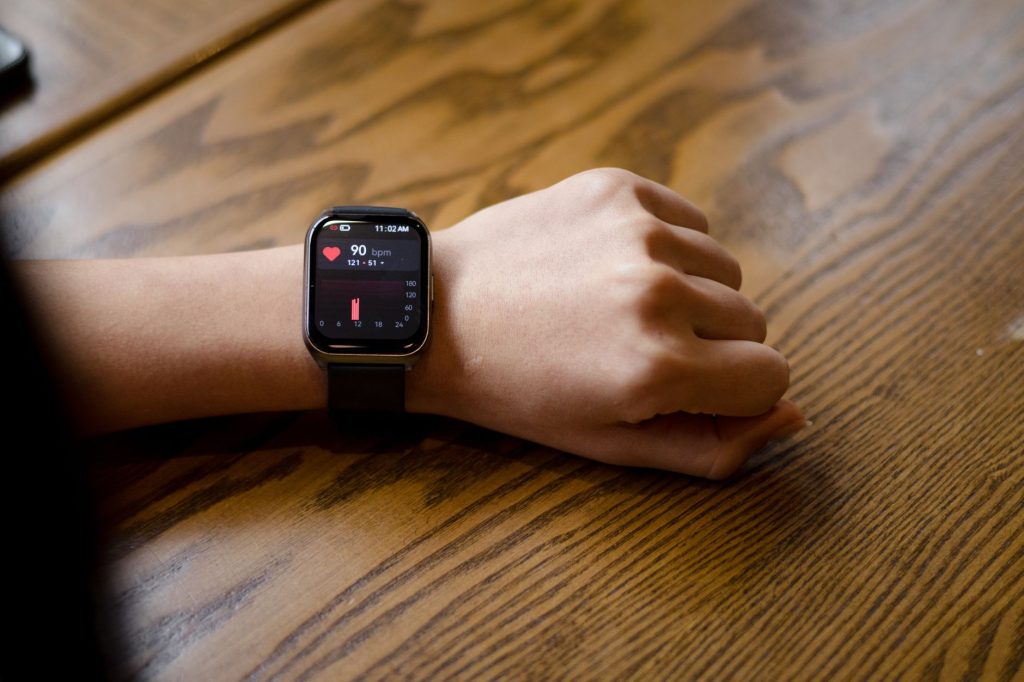 Gros plan d'une montre connectée affichant une fréquence cardiaque de 90 bpm au poignet