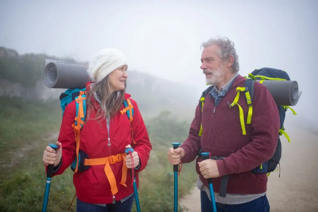 Couple senior randonnant avec bâtons de marche dans un paysage montagneux brumeux au Portugal