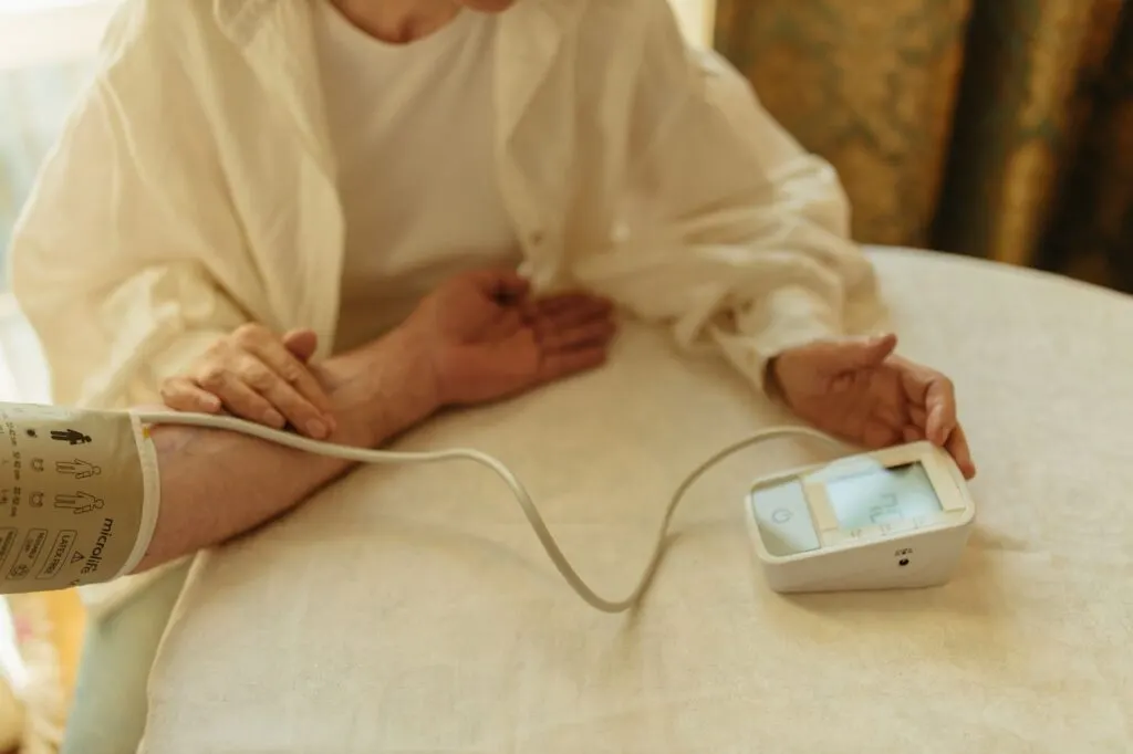 Une personne senior mesure sa tension artérielle avec un tensiomètre digital à domicile