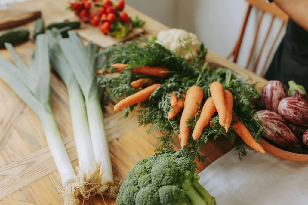 Assortiment coloré de légumes frais, carottes brocolis et poireaux, disposés sur une table en bois