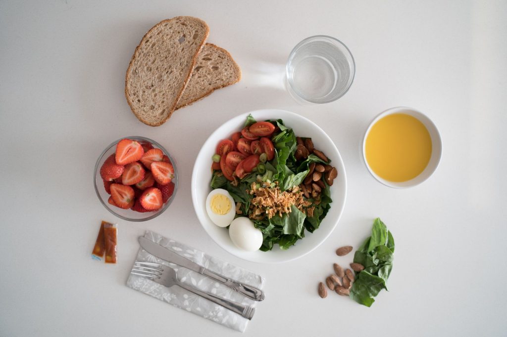 Vue de dessus d'un petit-déjeuner équilibré avec salade, œufs, pain et jus de fruit