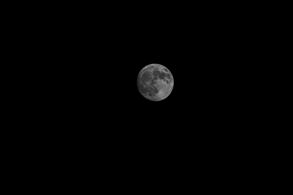 Vue captivante de la pleine lune contre un ciel nocturne sombre, image sobre et apaisante