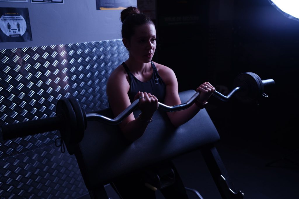 Femme concentrée soulevant une barre chargée dans une salle de sport, posture technique et déterminée