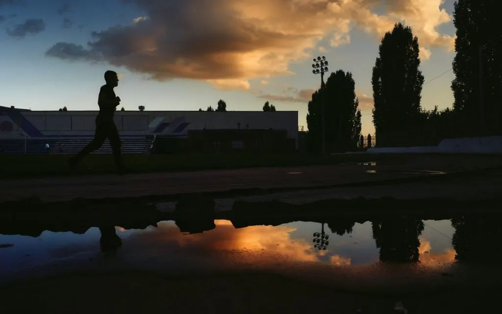 Silhouette d’un coureur au bord de l’eau, au coucher du soleil