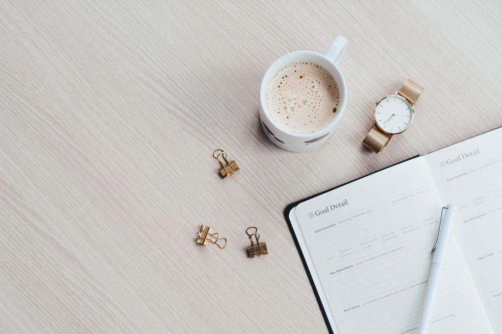 Agencement minimaliste de bureau avec tasse de café, carnet, stylo et montre-bracelet