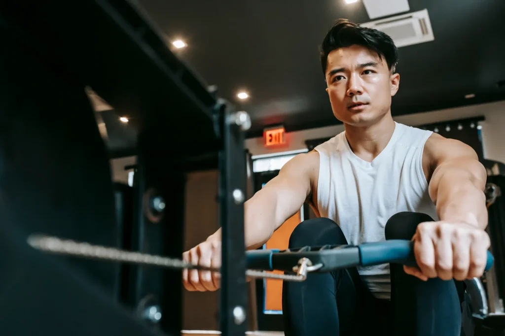 Vue en contre-plongée d'un homme musclé concentré s'entraînant sur une machine de sport